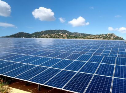 Solar Panels under clouds blue sky. Mountains in the background