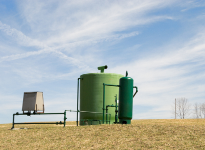 A green natural gas well in a field under sunny skies