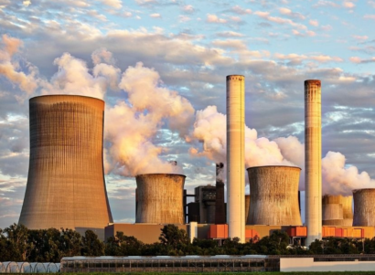 Active power plant emitting smoke into a cloudy sky.